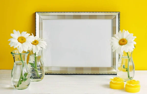Modèle de cadre blanc avec des fleurs de camomille dans des vases sur un fond jaune. Espace de copie — Photo