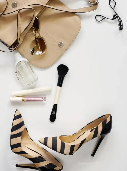 Vista superior de accesorios de moda femenina.Bolso de mano beige con gafas de sol, zapatos de tacón alto, perfume y cosméticos sobre fondo blanco . — Foto de Stock