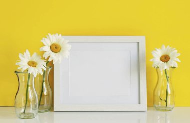 Beyaz bir çerçeve mockup papatya çiçek vazolar üzerinde sarı bir arka plan ile. Kopya alanı