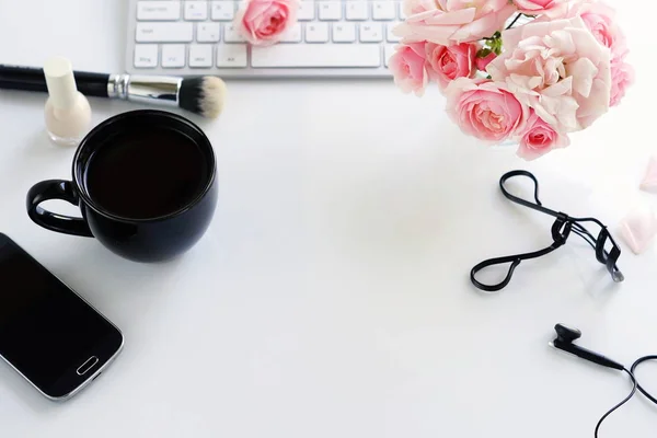 Vrouwelijke Bureau plat lag, top uitzicht, vrouwelijke make-up accessoires, werkruimte met laptop, telefoon, kopje koffie en een boeket rozen. Beauty blog concept. Kopiëren van ruimte — Stockfoto