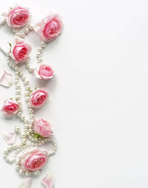 A frame of pink roses and beads on a white background.Top view. Copy space — Stock Photo, Image