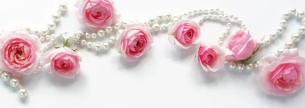 A frame of pink roses and beads on a white background.Top view. Copy space — Stock Photo, Image