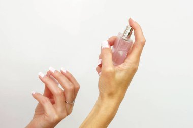 Beyaz zemin üzerinde bir parfüm şişesi tutan eller