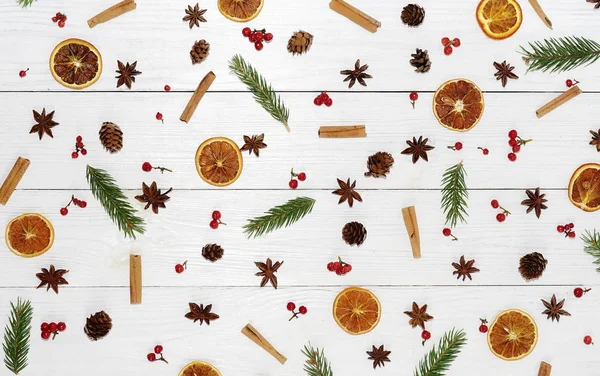 Autumn winter pattern composition of branches of an tree, cinnamon, dried orange, anise of stars and berries on white wooden background.Top view. Flat lay