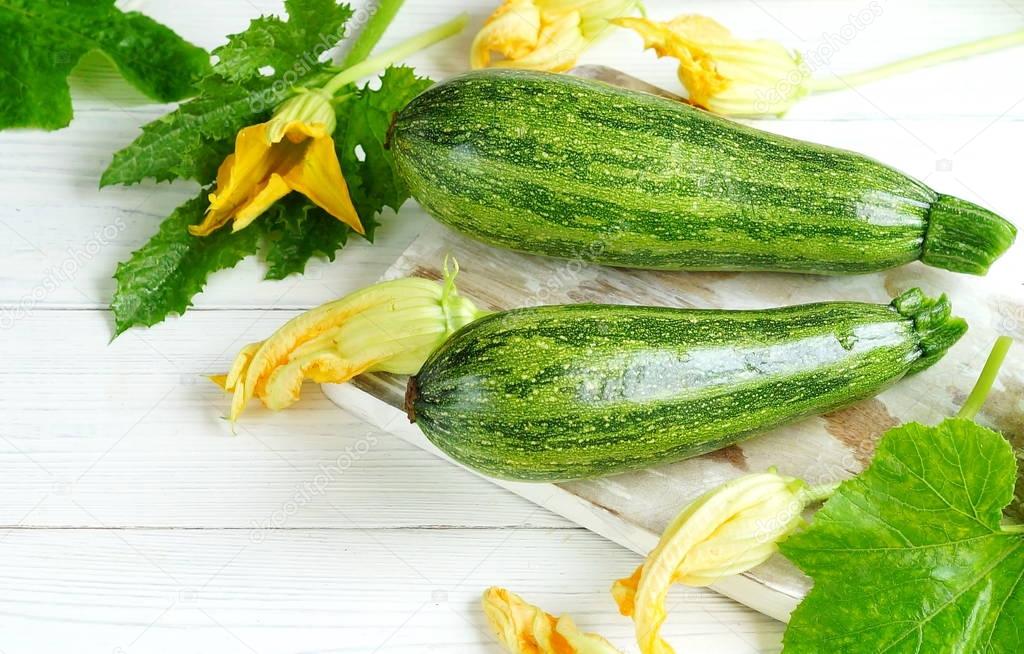 A fresh zucchini squash on a white wooden background. Top view. Copy space