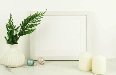 Mazı (bitki) dallarında beyaz vazo, Noel topları, mumlar ile beyaz çerçeve. 