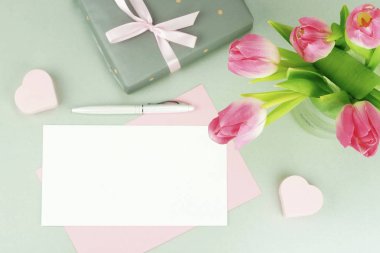 Kadınsı Danışma, güzel Pembe Lale vazo, hediye ve gri bir arka plan üzerinde metin için bir kart bir buket ile çalışma alanı. düz yatıyordu. Üstten Görünüm. kopya alanı