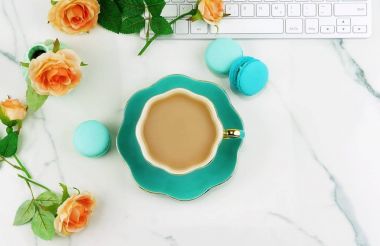 bilgisayar, güzel güller çiçek, fincan kakao ve bir mermer background.women'ın masasında macaroons ile tablo Masası çalışma alanı. Tatil arka plan. Üstten Görünüm. Kopya alanı