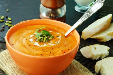 Krem ve koyu ahşap zemin üzerine maydanoz ile kabak ve havuç çorbası. Üstten Görünüm. Yakın çekim. 