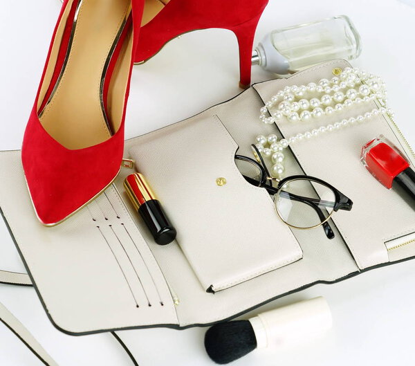 Female fashionable stylish accessories and cosmetics. red shoes with heels, white bag, perfume, glasses, lipstick, red nail polish on a white background. Beauty blog concept. Top view. Flat lay