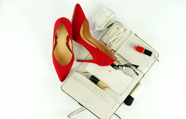 Female fashionable stylish accessories and cosmetics. red shoes with heels, white bag, perfume, glasses, lipstick, red nail polish on a white background. Beauty blog concept. Top view. Flat lay