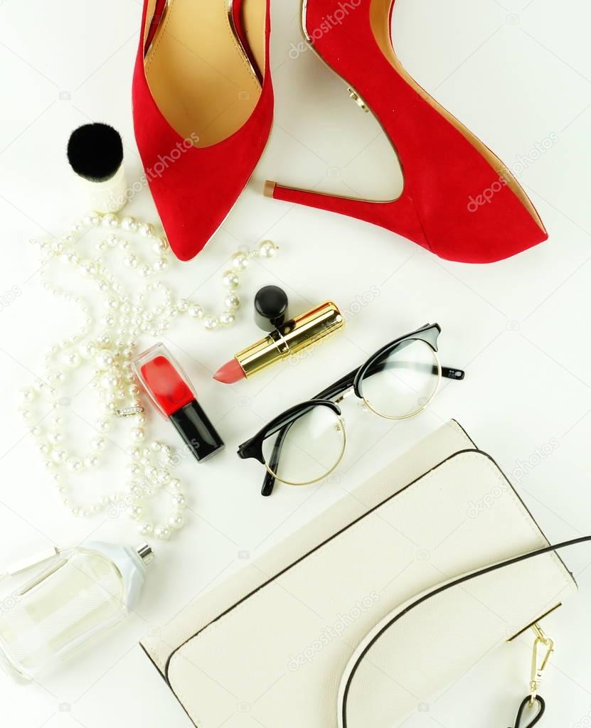 Female fashionable stylish accessories and cosmetics. red shoes with heels, white bag, perfume, glasses, lipstick, red nail polish on a white background. Beauty blog concept. Top view. Flat lay