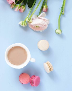Macaroons çiçekler ve soluk mavi zemin üzerine kakao fincan ile pastel renklerde. Üstten Görünüm