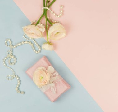Pembe tipik çiçekler, hediye kutusu ve mavi soluk pembe renkli inci kolye. Üstten Görünüm. Kopya alanı