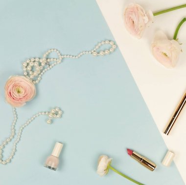 Pembe tipik çiçekler, kozmetik ve mavi soluk pembe renkli inci kolye. Üstten Görünüm