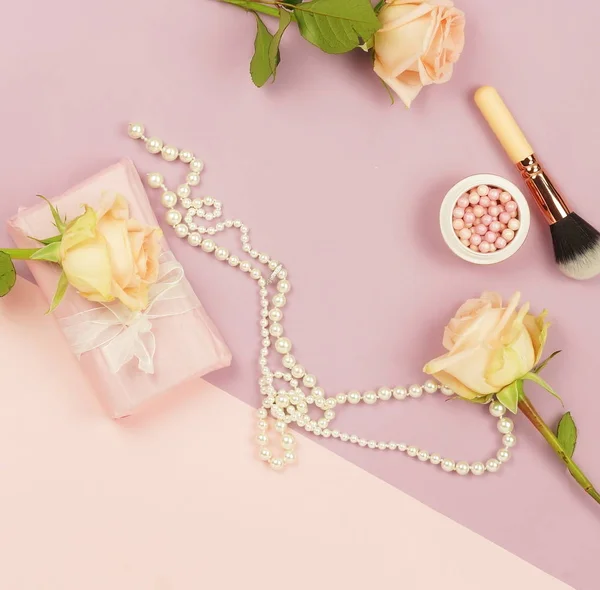 Fresh rose flowers, present box, cosmetics and pearl necklace on pale pink purple background. Top view.Copy space