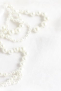 Blure etkisi, beyaz keten kumaş arka plan üzerinde yumuşak odak kadın inci boncuk süsleme. Üstten Görünüm. Kopya alanı