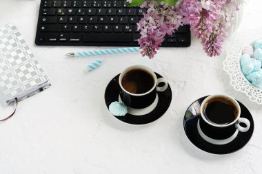 Ev ofis büro. klavye, bardak kahve, defter, gözlük ve beyaz arka plan üzerinde bir vazoda Eflatun çiçekler buket ile kadın çalışma alanı. Uzay kopyalayın. Üstten Görünüm