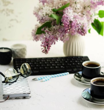 Ev ofis büro. klavye, bardak kahve, defter, gözlük ve beyaz arka plan üzerinde bir vazoda Eflatun çiçekler buket ile kadın çalışma alanı. Uzay kopyalayın. Üstten Görünüm