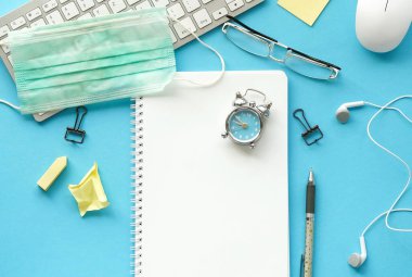 Coronavirus Covid - 19 karantina, evde kal, evden çalış. Mavi arkaplanda ofis masası üstü görünümü. Kopya alanı