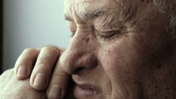 Sad eyes: thoughtful old man sitting alone at home near the window: — Stock Video