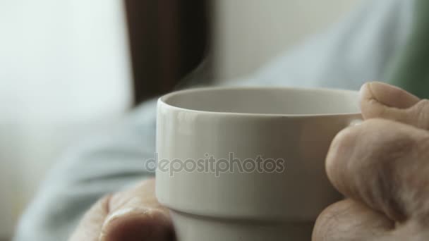 Manos de anciano con una taza de café caliente — Vídeo de stock