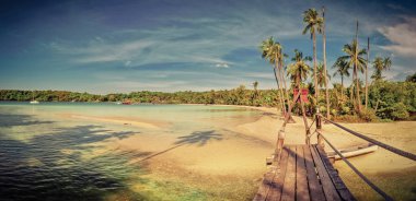 Palmiye ağaçları, beyaz kum, turkuaz okyanus su ve mavi gökyüzü ile güzel tropikal plaj