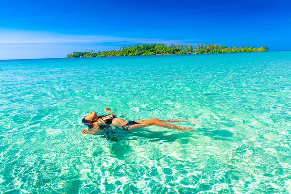 Woman in bikini lying on water at tropical beach — Stock Photo, Image