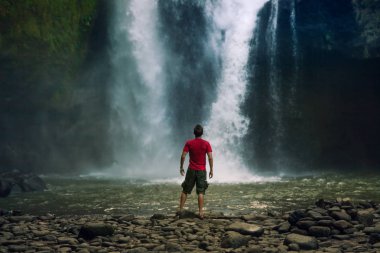 genç adam backpacker ormanlarda şelale bakarak