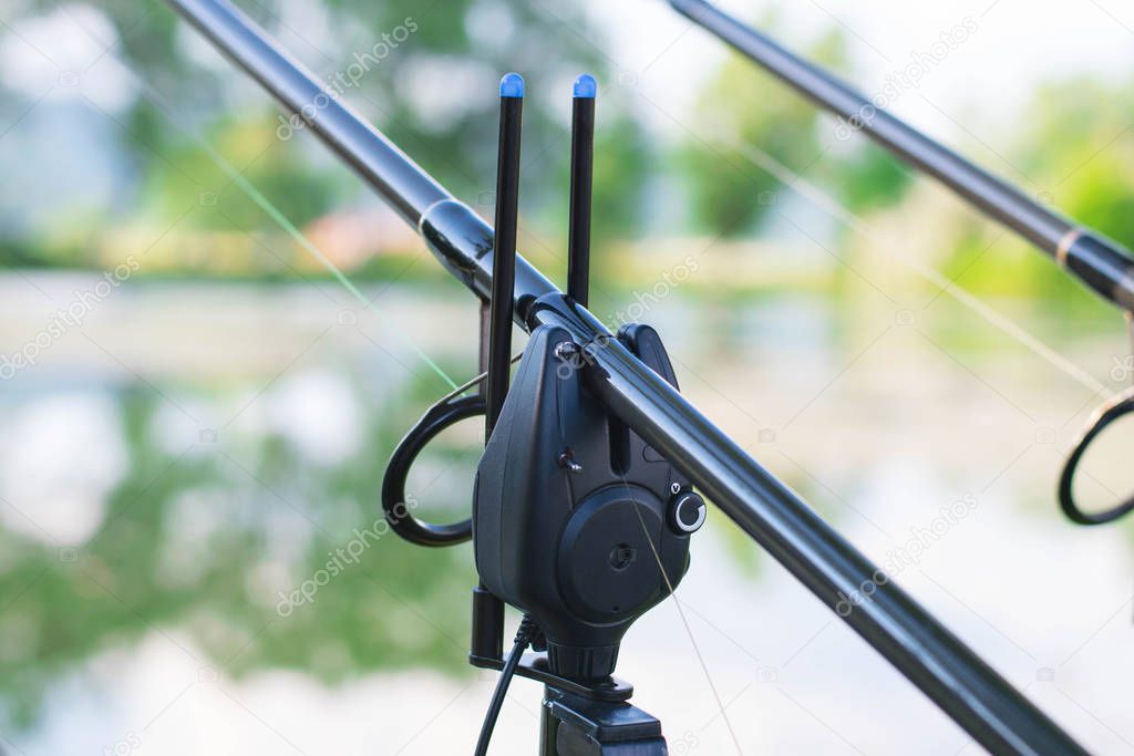 Professional carp fishing bite alarm, close-up from lakeside background.