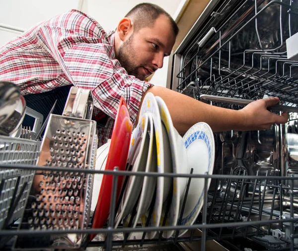 Handsome guy repair dishwasher in  the kitchen