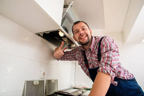 Handsome guy work on ventilation in the kitchen