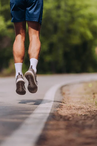 Schuss auf sportlichen hemdlosen jungen Mann, der auf Bergstraße in b rennt — Stockfoto