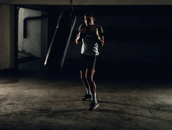 Silhouette muskulöse Kämpfer Training auf einem Boxsack in der gy — Stockfoto