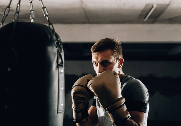 Boxeador agresivo en entrenamiento de guantes de boxeo con saco de boxeo — Foto de Stock