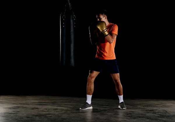 Ajuste o homem de boxe profissional chutando no saco de perfuração — Fotografia de Stock