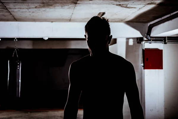 Σιλουέτα ενός ανθρώπου γυμναστήριο που στέκεται πάνω από το σκούρο φόντο — Φωτογραφία Αρχείου