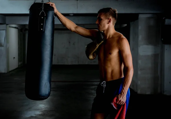 Фитнес-человек стоит рядом с боксерской грушей и готовится к упражнениям — стоковое фото