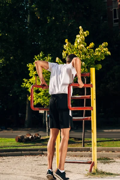 Trainierender Fitness-Athlet Mann trainiert Tauchgänge auf Metallstangen in na — Stockfoto