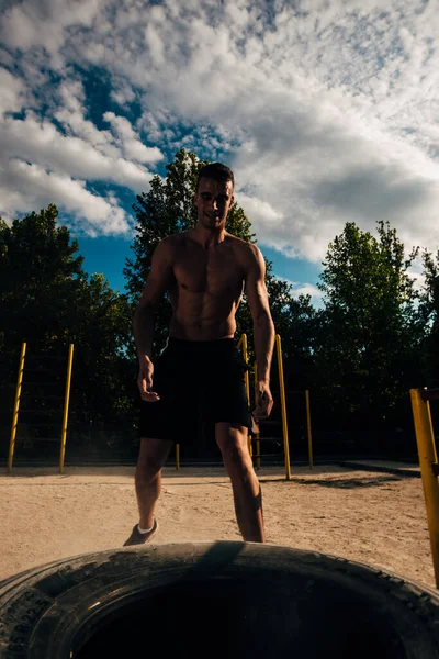 Knap shirtloos bezwete sportman tillen band in de buitenlucht sportschool — Stockfoto