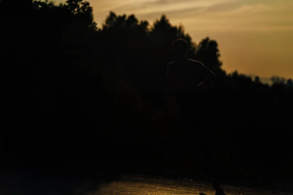 Silueta masculina corriendo en las montañas bajo la luz del sol — Foto de Stock