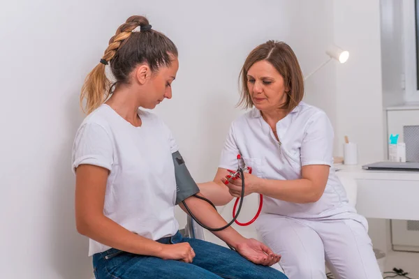 Médica do sexo feminino medindo a pressão arterial de sua jovem adolescente pat — Fotografia de Stock