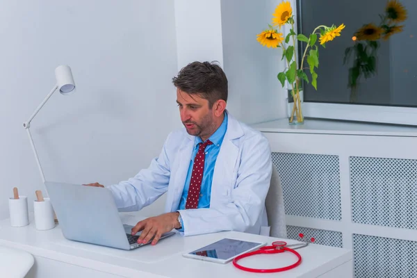 Männliche ernsthafte kaukasische Arzt sitzt in seinem Büro allein und th — Stockfoto