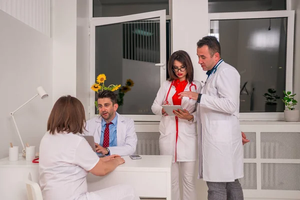 Grupa lekarzy stojących i dyskutujących patrząc na — Zdjęcie stockowe
