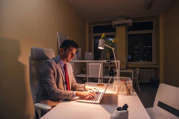 Ernsthafter Arzt arbeitet nachts an seinem Laptop (PC), Überstunden. — Stockfoto