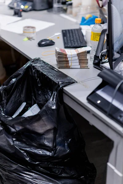 Liczenie biurko z czarną torbą plactic i gotówką na nim — Zdjęcie stockowe