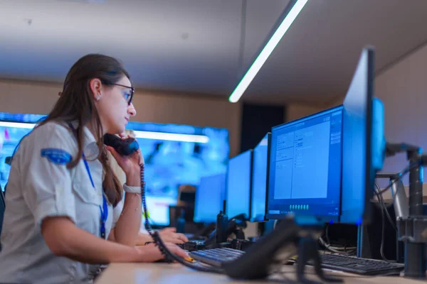 Female security guard operator talking on the phone while watching the computer ( cctv monitors ).