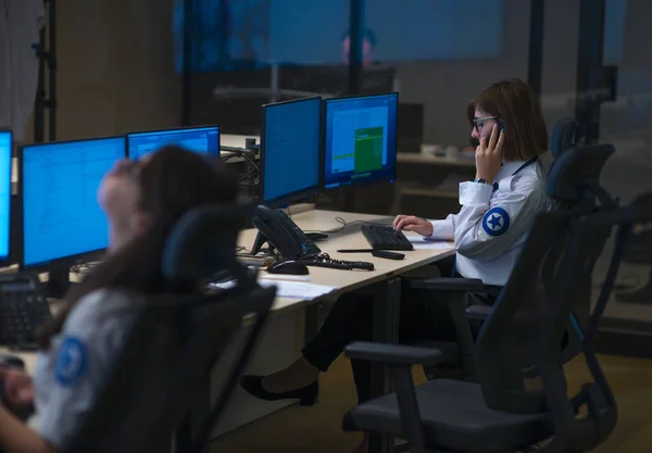 Security guard monitoring modern CCTV cameras in a surveillance room. Group of security guards sitting and monitoring.