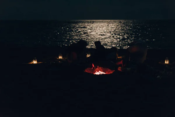 Amigos desfrutando de música perto da fogueira à noite na praia — Fotografia de Stock