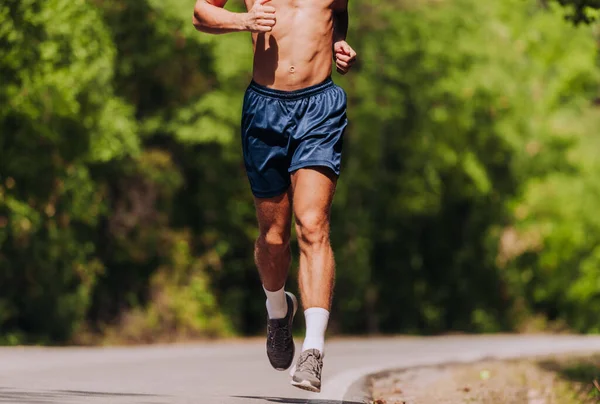 驚くべき自然の風景の中で森の道路上のマラソンのためのトレーニングを実施するために 男性のフィットネスモデルをジョギング — ストック写真